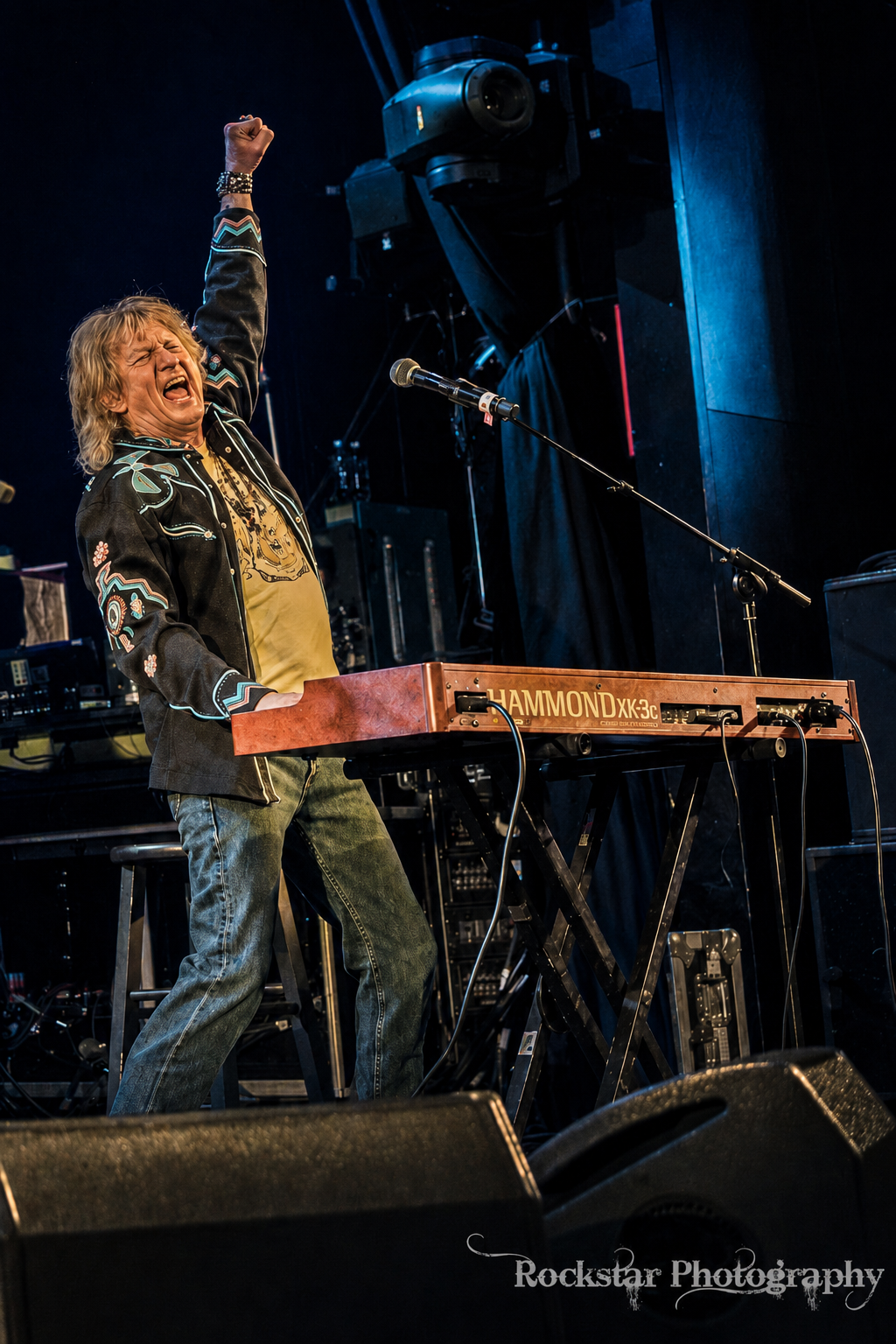 Eddie Stone performing live with his Hammond XK-3c keyboard, fist raised triumphantly on stage